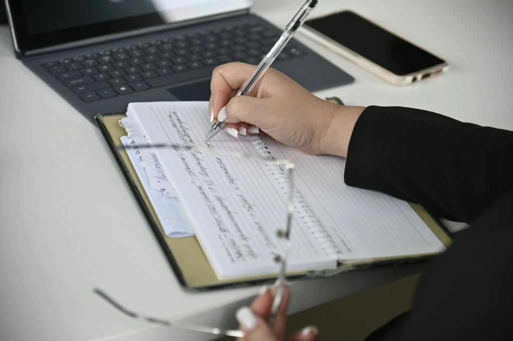 Inefficient HR processes A person writing on a notebook with a laptop in the background