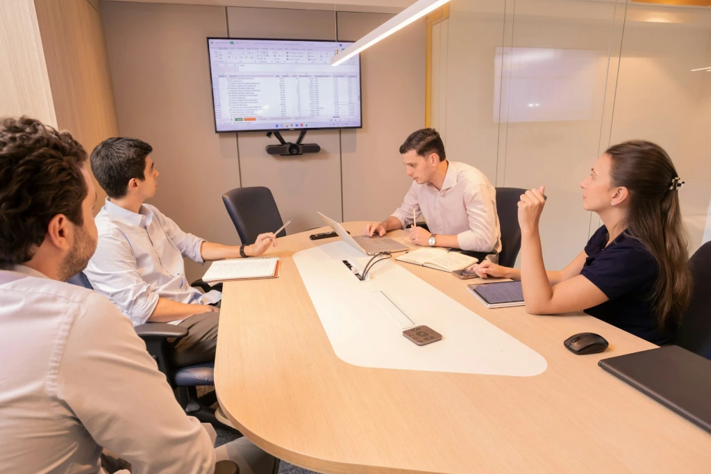 Poor communication between teams Business meeting with people around a conference table.